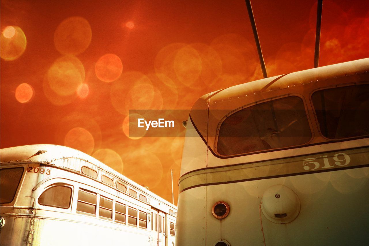 Low angle view of old buses against orange sky
