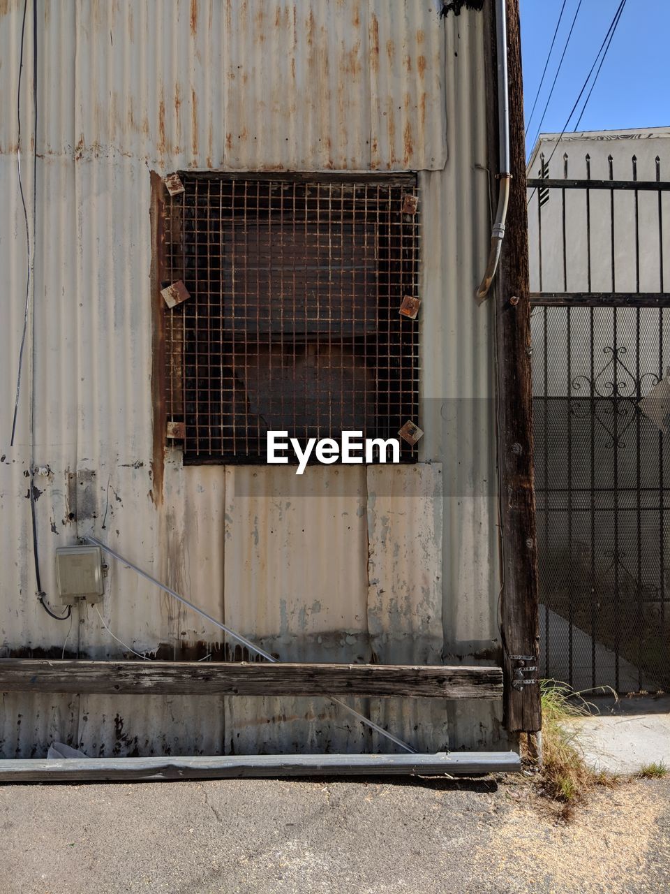 ABANDONED BUILDING SEEN THROUGH METAL FENCE