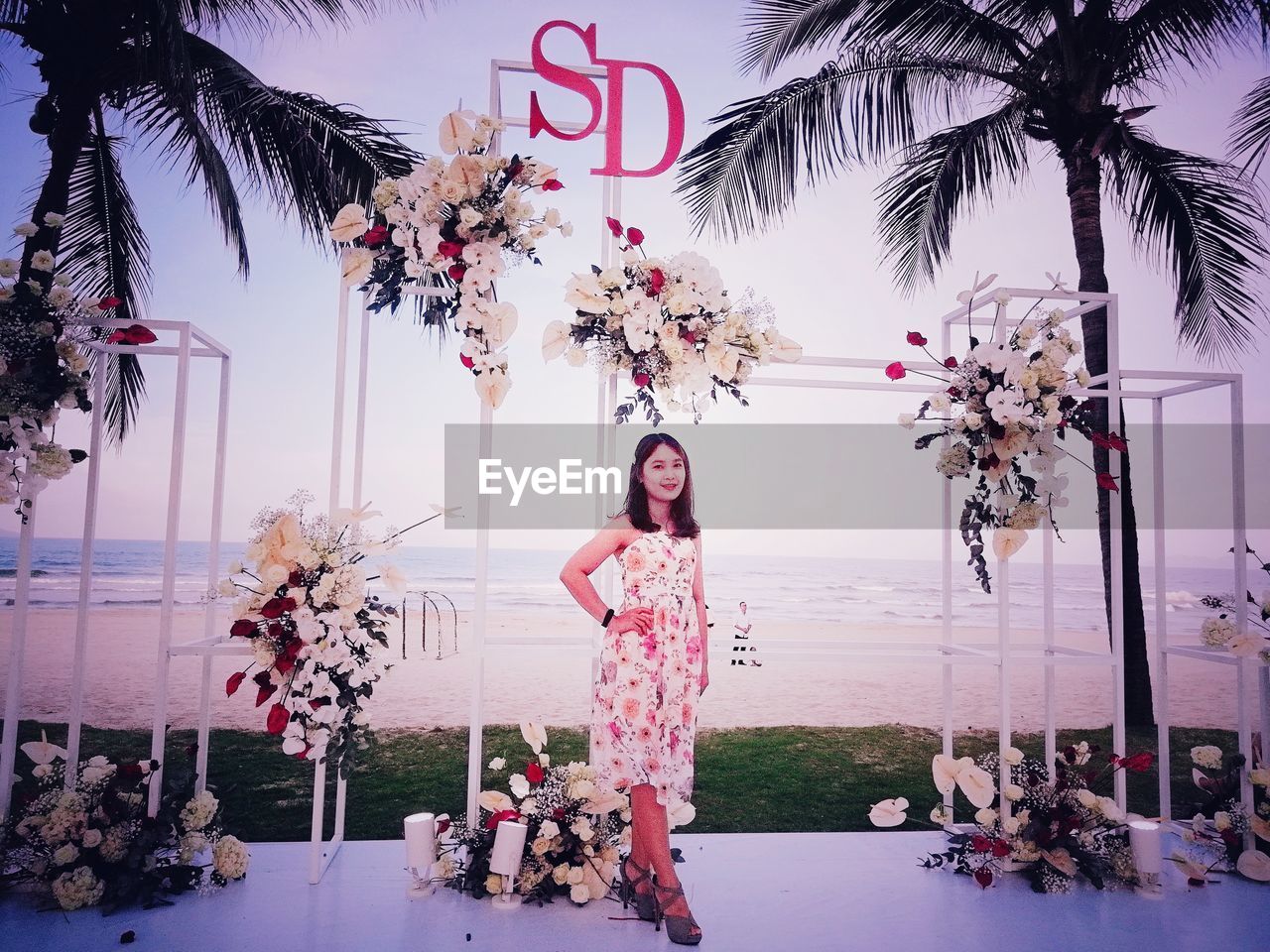 PORTRAIT OF WOMAN STANDING BY PALM TREES