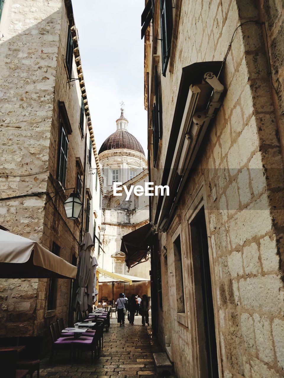 PEOPLE WALKING ON ALLEY AMIDST BUILDINGS