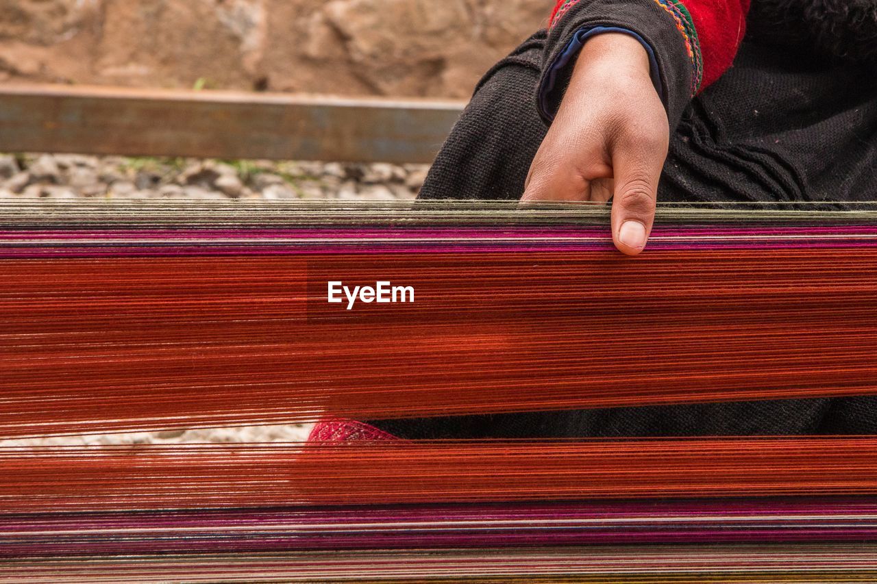 Cropped image of woman weaving thread