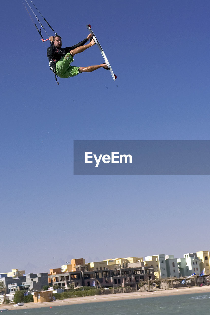 LOW ANGLE VIEW OF PERSON JUMPING AGAINST CLEAR SKY