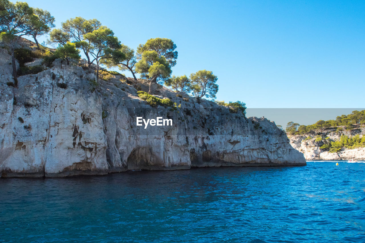Scenic view of sea and rocks against clear sky
