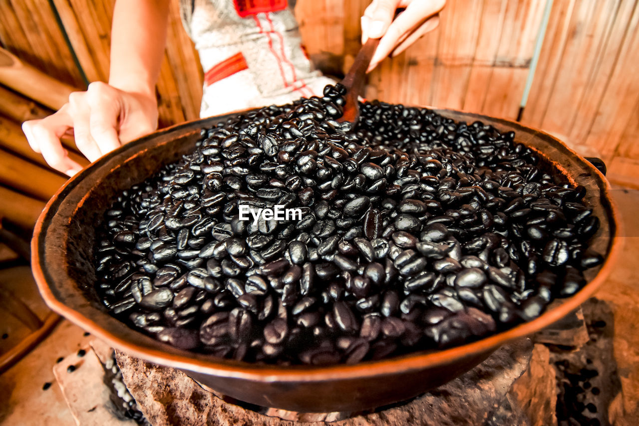 Close-up of woman holding coffee bean in bowl