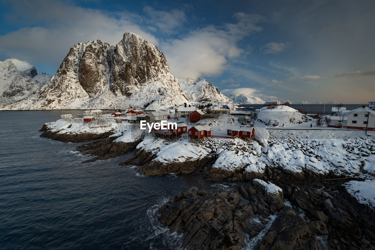 Scenic view of sea by mountain against sky