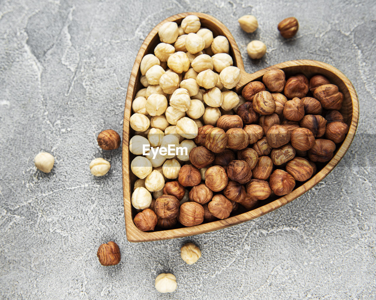 Peeled hazelnuts in a bowl on grey concrete background