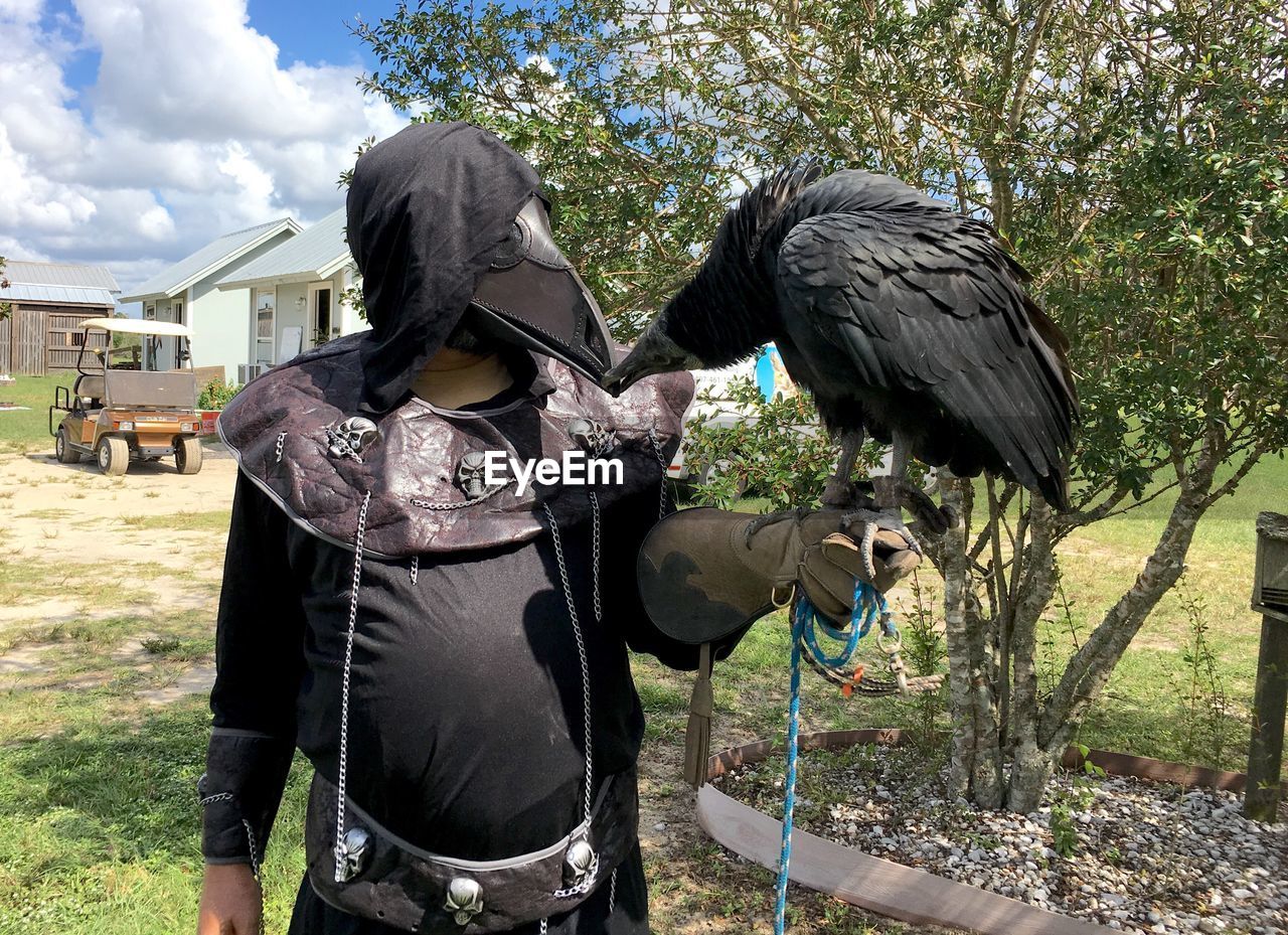 MIDSECTION OF MAN STANDING BY PIGEONS