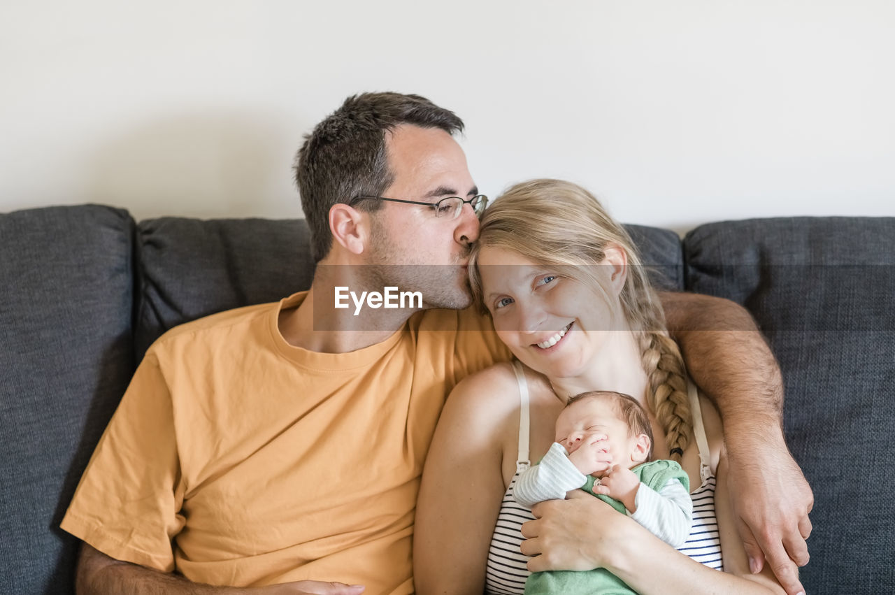 Man kissing woman sitting with baby
