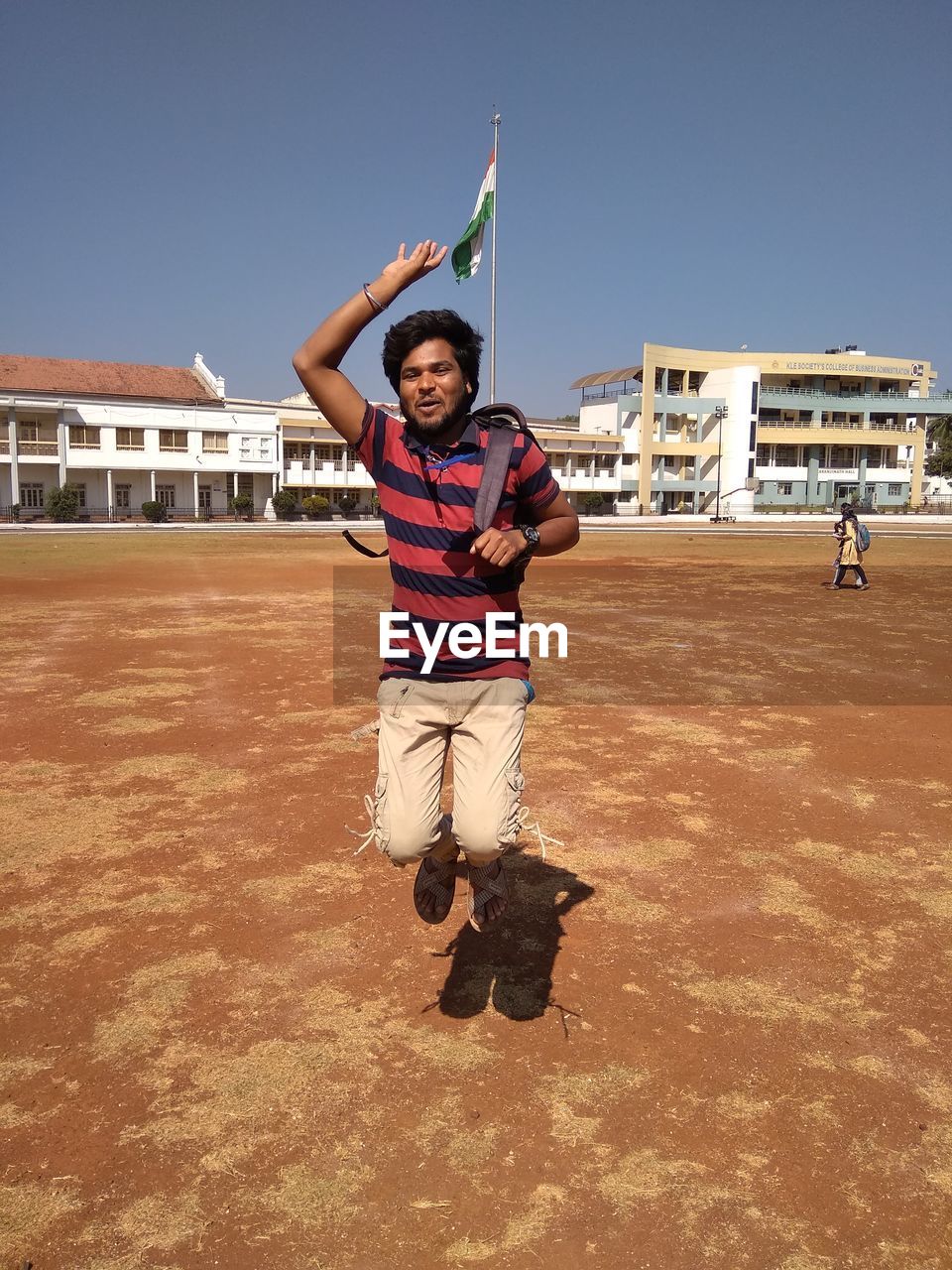 Portrait of young man jumping on land against built structure