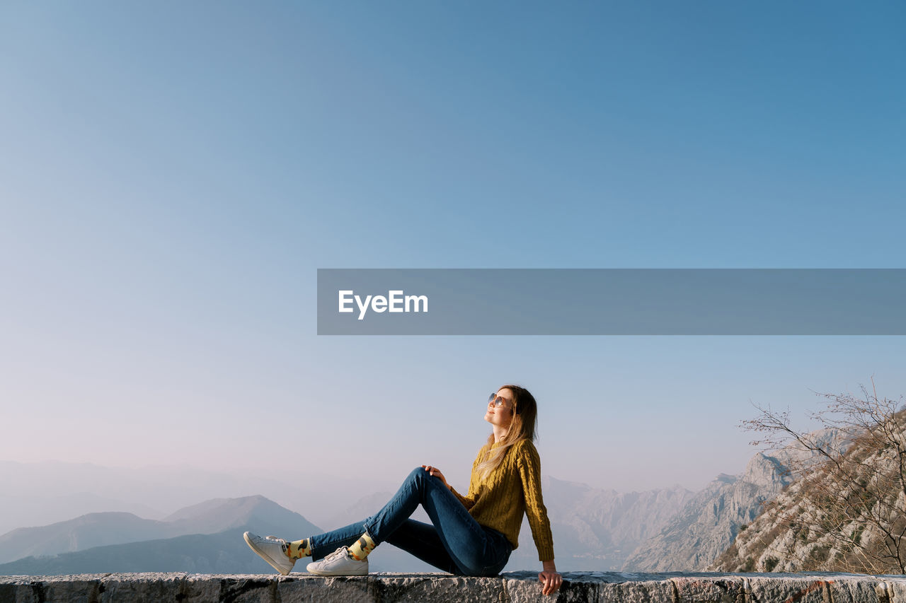 low angle view of woman standing on mountain against clear sky