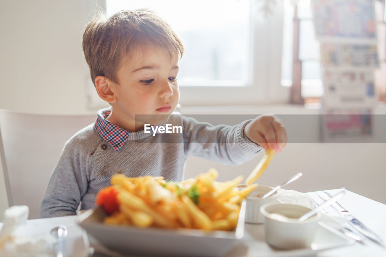 Boy eating food on table