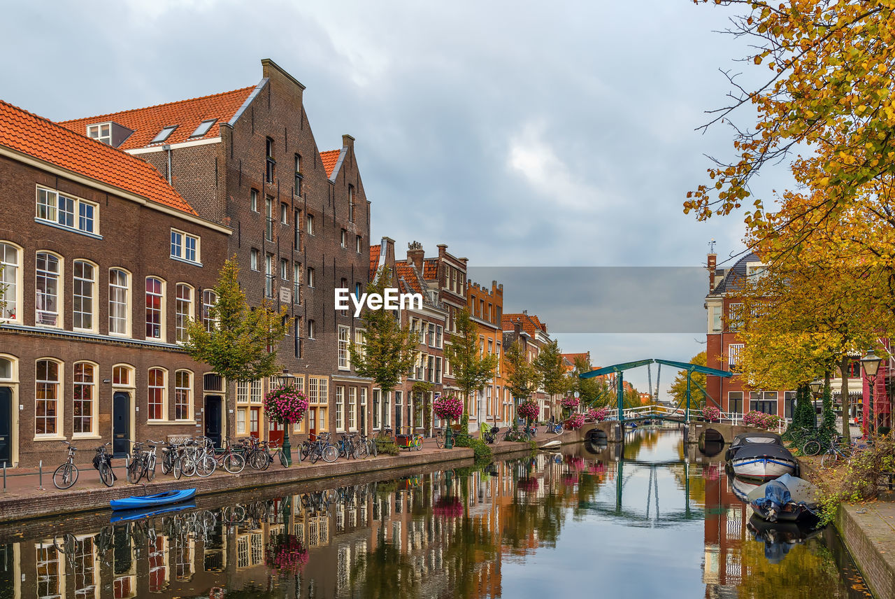 ARCH BRIDGE OVER CANAL AMIDST BUILDINGS IN CITY AGAINST SKY