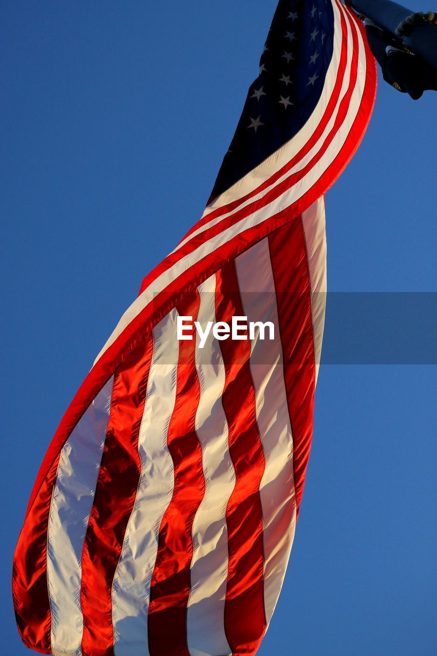 Low angle view of flag against clear blue sky