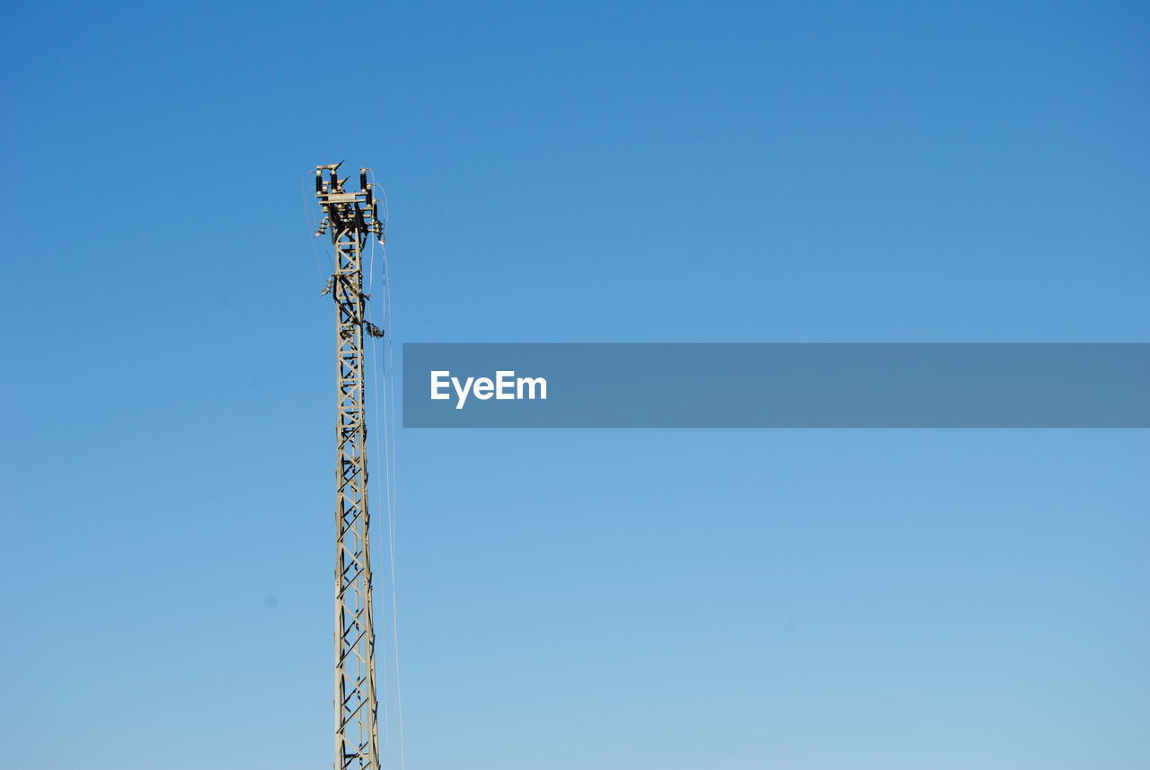 Low angle view of crane against clear blue sky