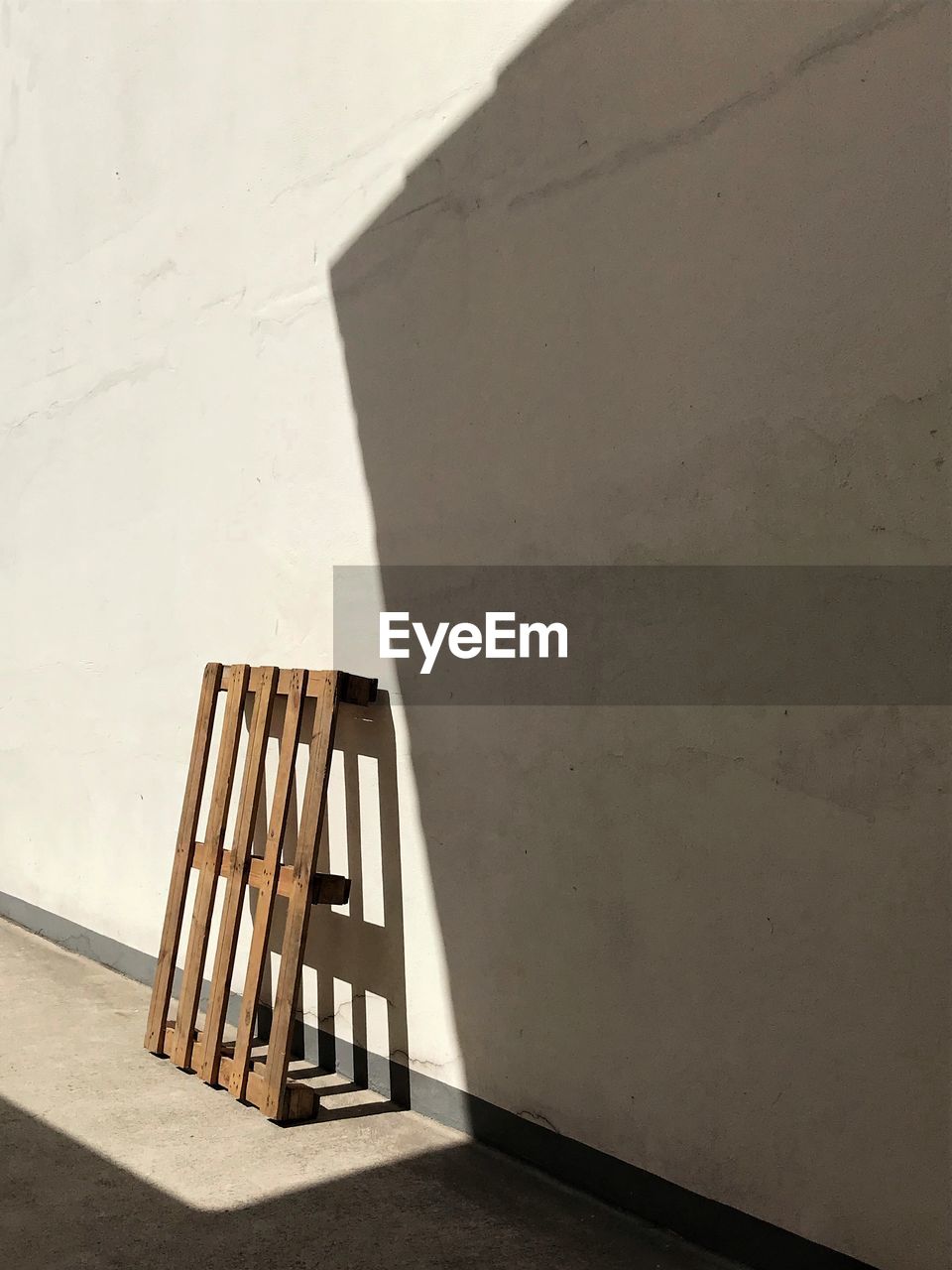 Empty pallet against wall on sunny day