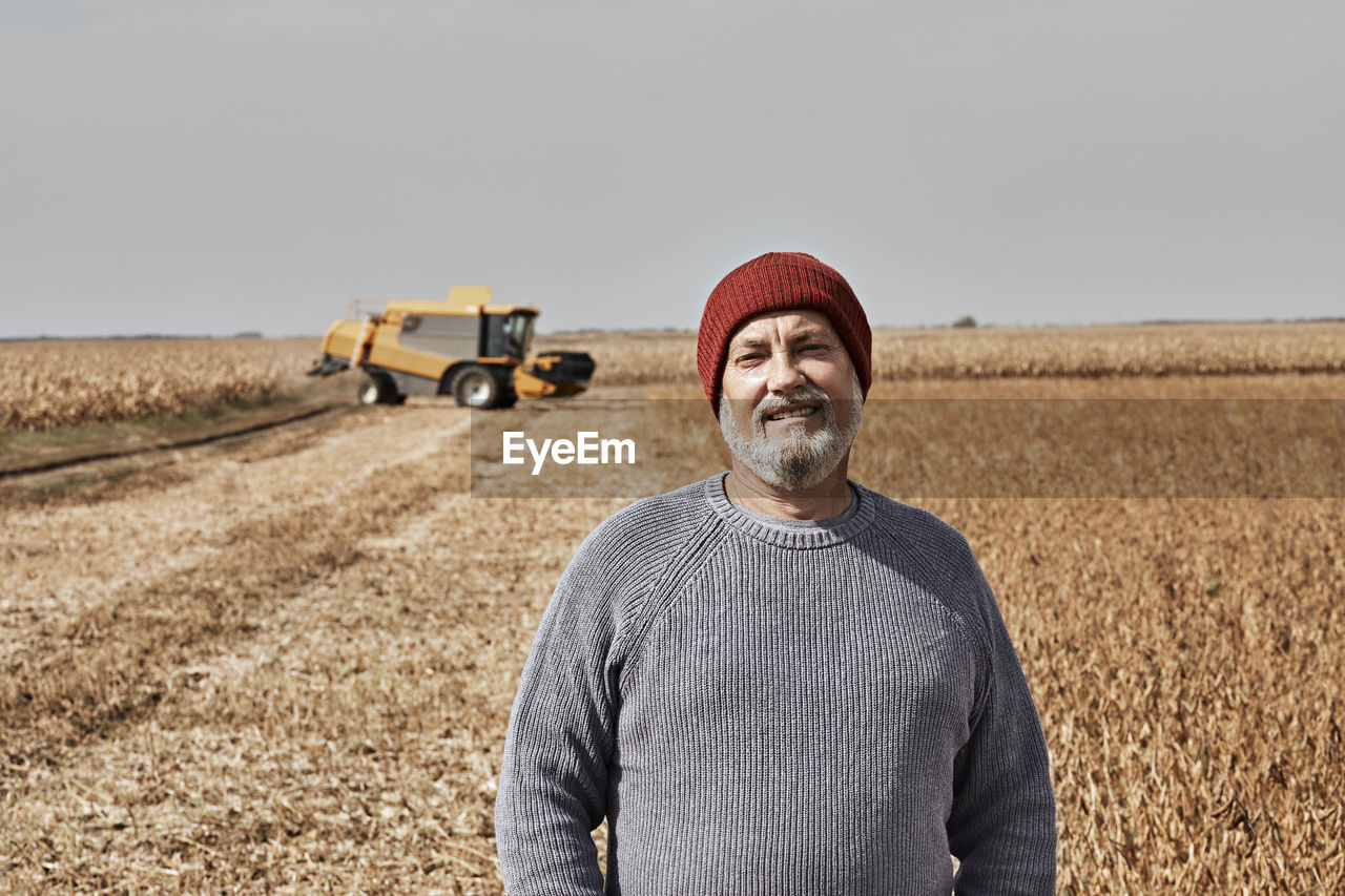 Smiling farmer standing at field during sunny day