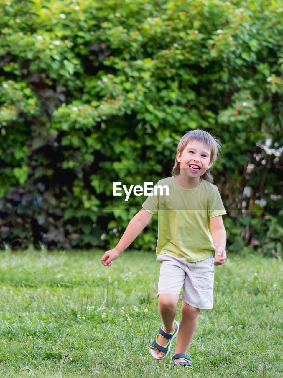 Laughing kid runs on grass lawn at backyard. childhood. vacation. cheerful child plays outdoors. 