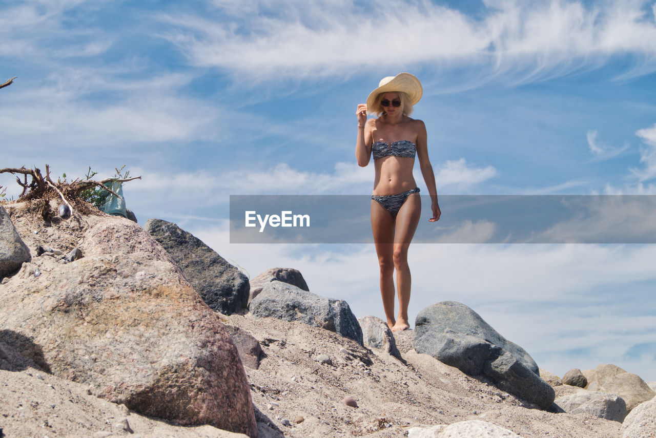 Woman wearing bikini while walking on land against sky