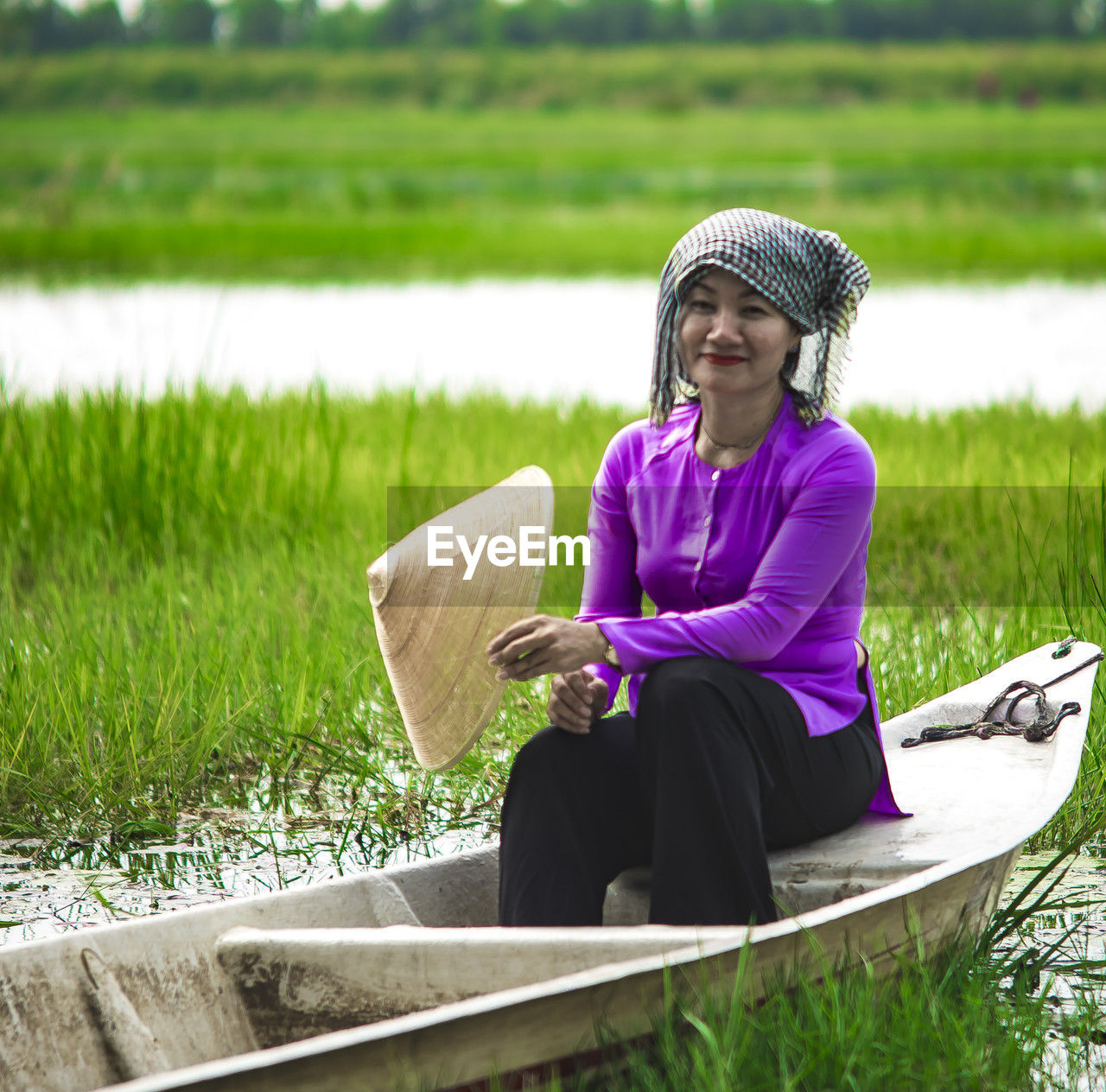 adult, one person, women, plant, sitting, nature, grass, water, relaxation, lifestyles, female, clothing, landscape, leisure activity, rural scene, tranquility, lake, senior adult, outdoors, green, activity, paddy field, full length, day, field, mature adult, smiling, casual clothing, person, hat, purple, agriculture, tranquil scene, emotion, seniors, looking, environment, beauty in nature