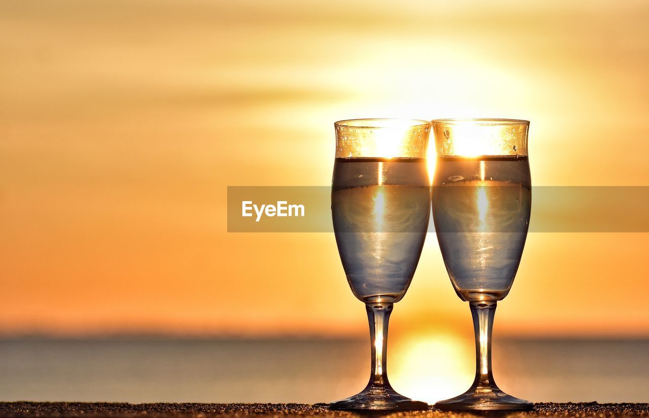 CLOSE-UP OF WINE GLASS AGAINST SUNSET SKY