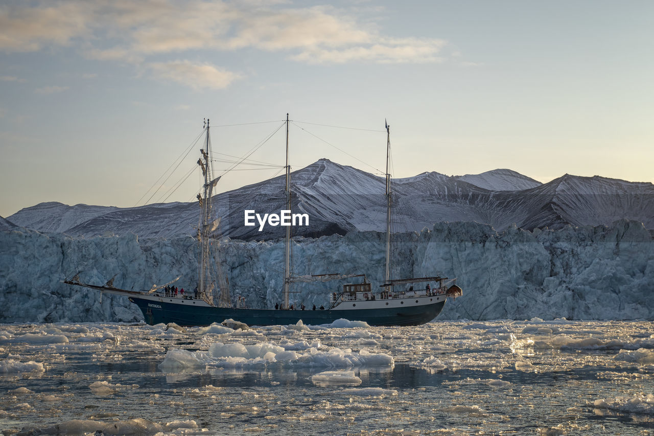 SAILBOAT ON SEA AGAINST MOUNTAINS