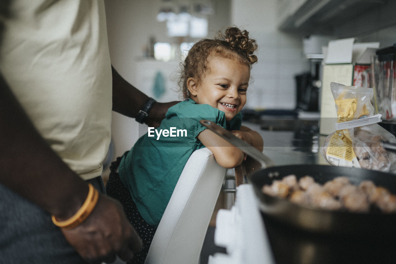 Happy girl looking at meal being cooked by father