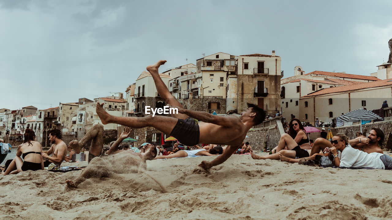 GROUP OF PEOPLE ON BEACH AGAINST SKY