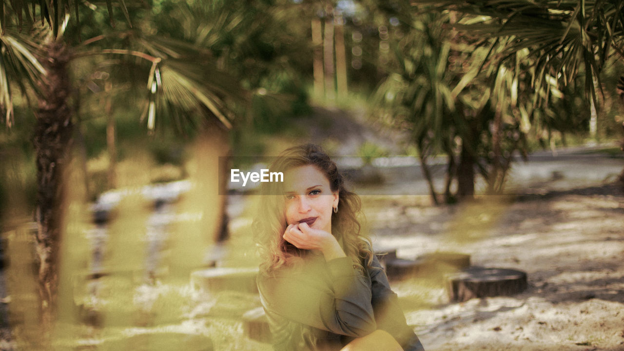 Portrait of smiling young woman against trees