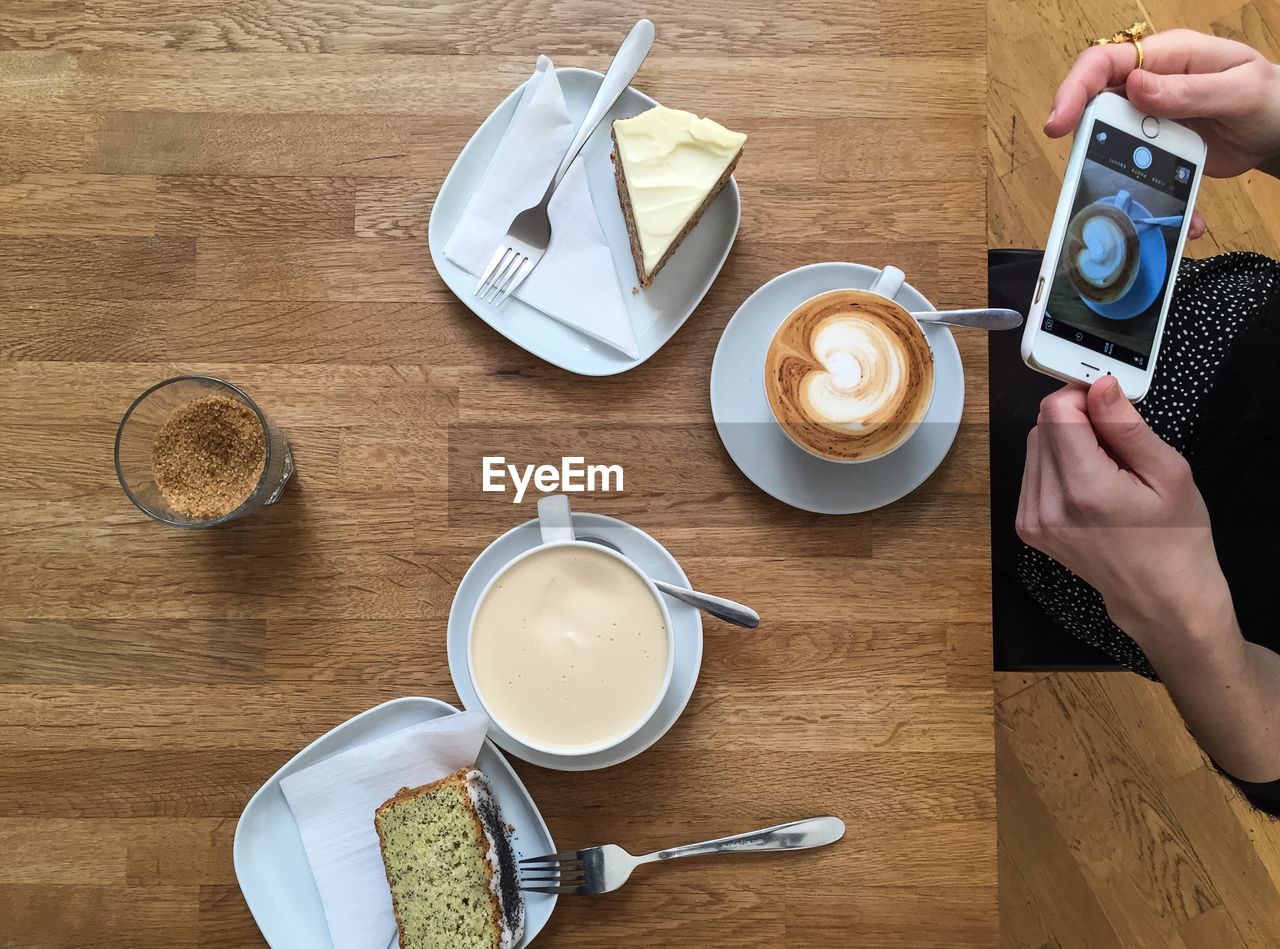 Midsection of woman photographing coffee while sitting at table