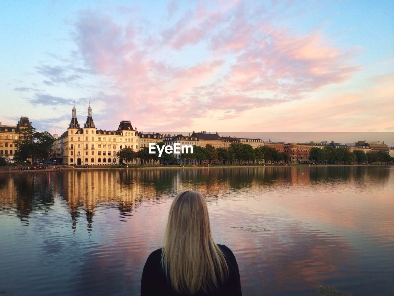 Rear view of woman watching lake and buildings