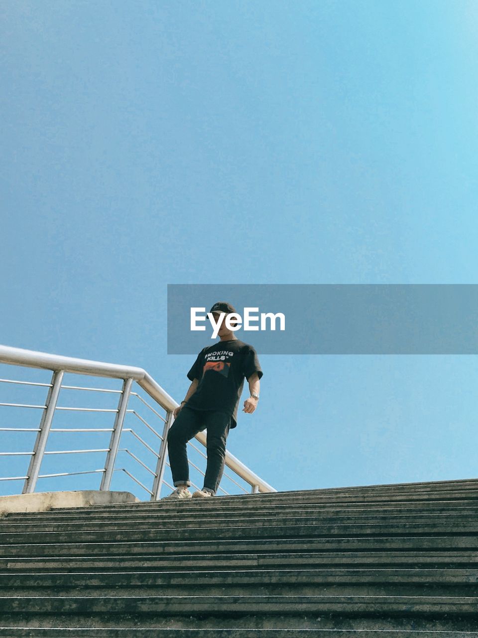 LOW ANGLE VIEW OF PERSON ON STAIRCASE AGAINST CLEAR SKY