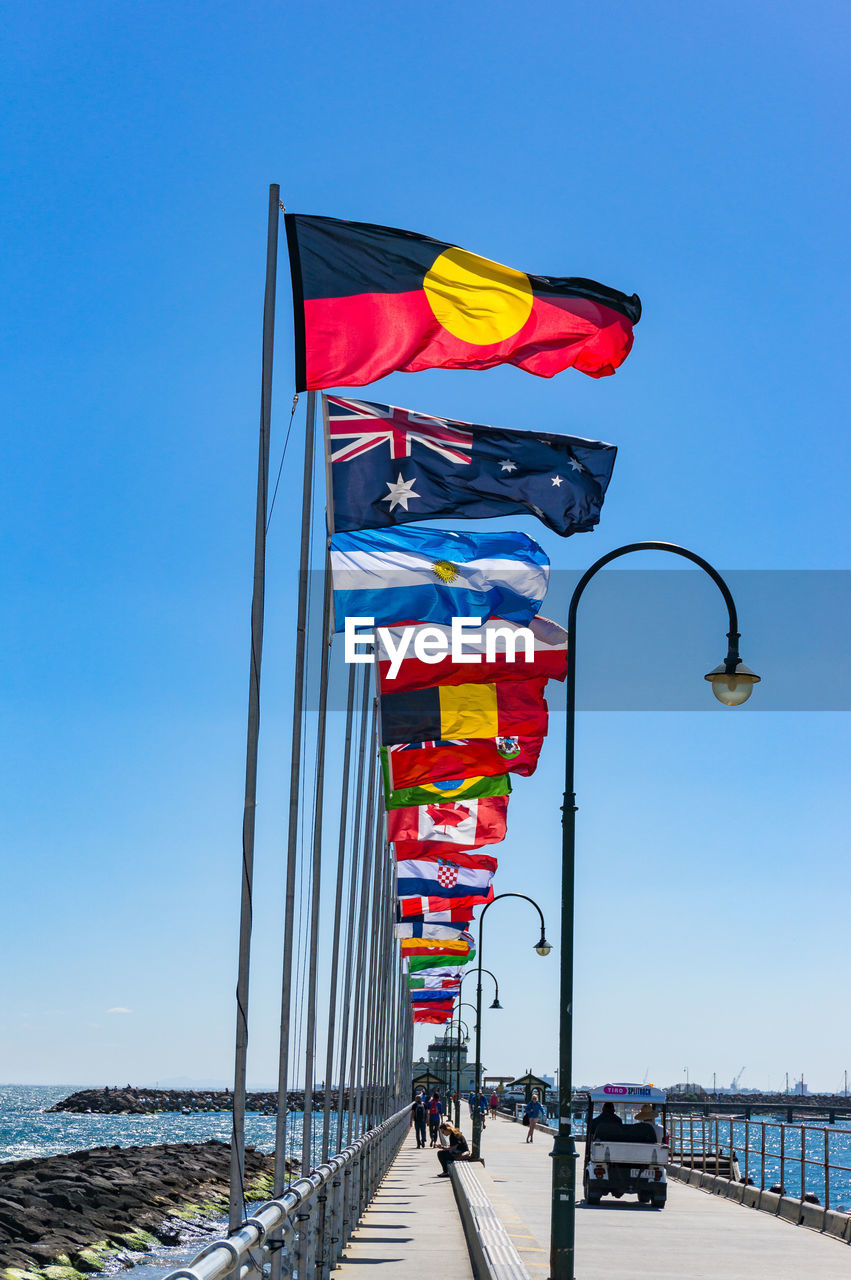 St kilda pier with rows of national flags with australian aboriginal flag