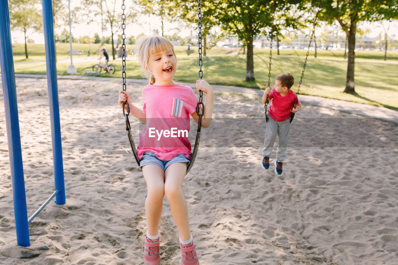 Siblings swinging at park