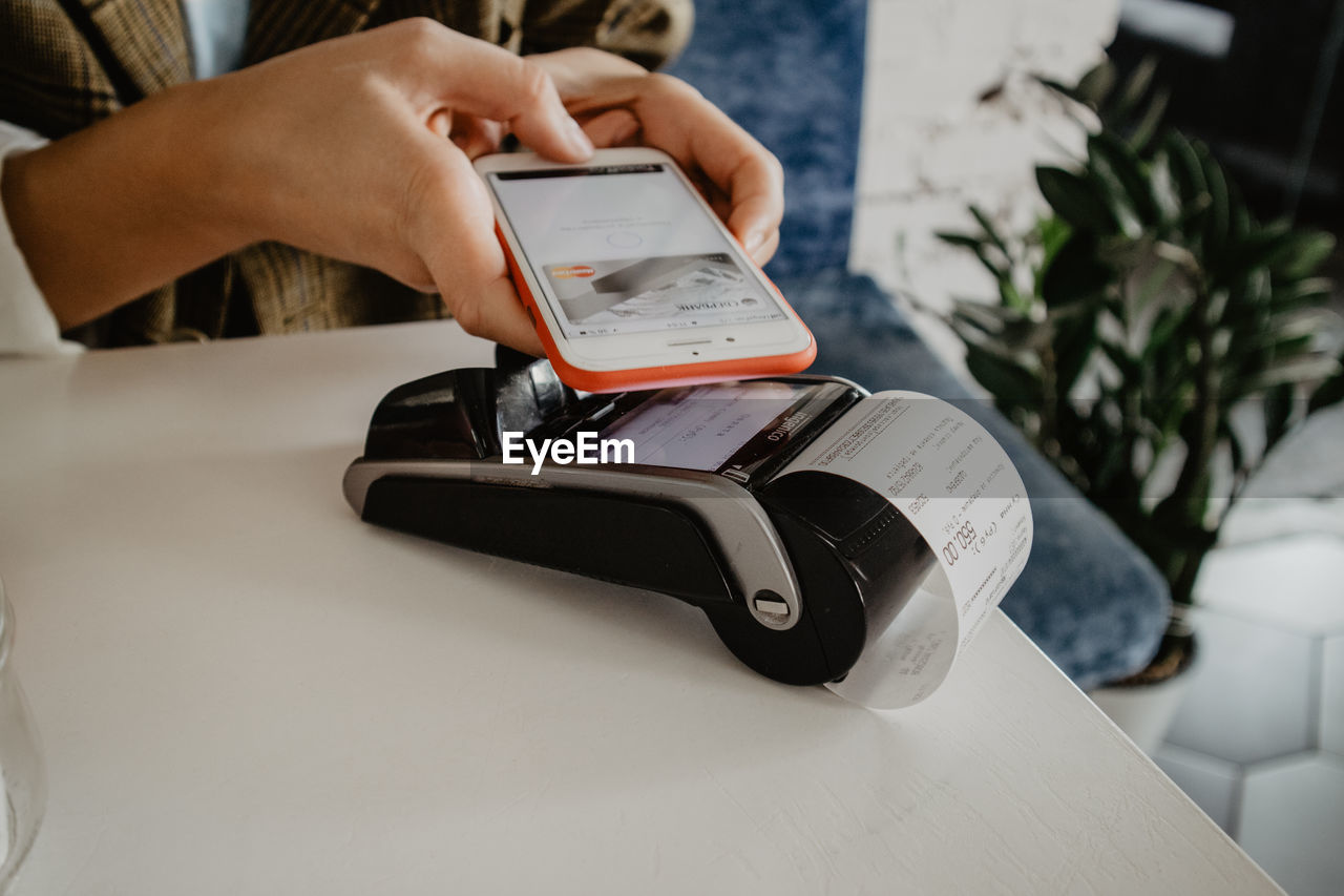 MAN USING SMART PHONE ON TABLE