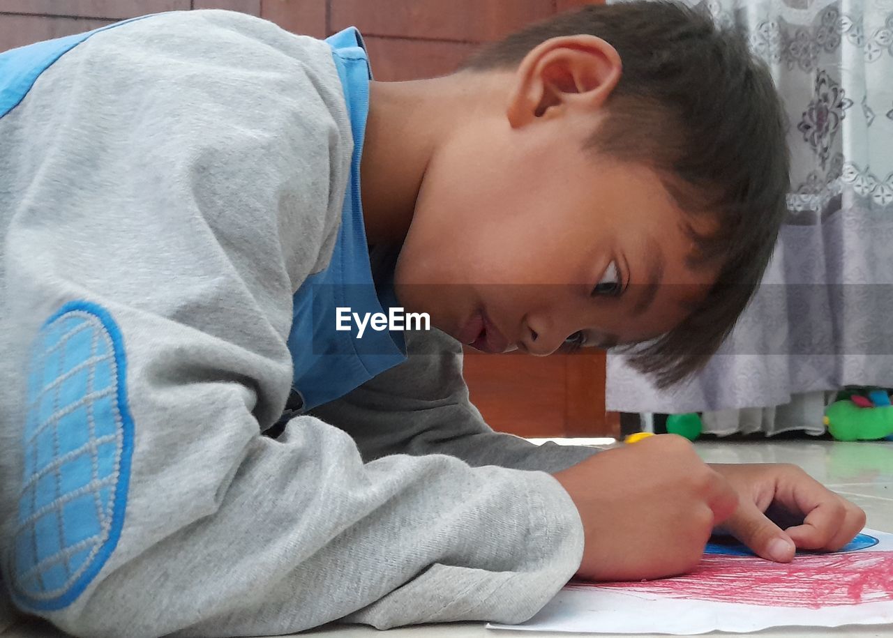 Close-up of boy is coloring picture  at home