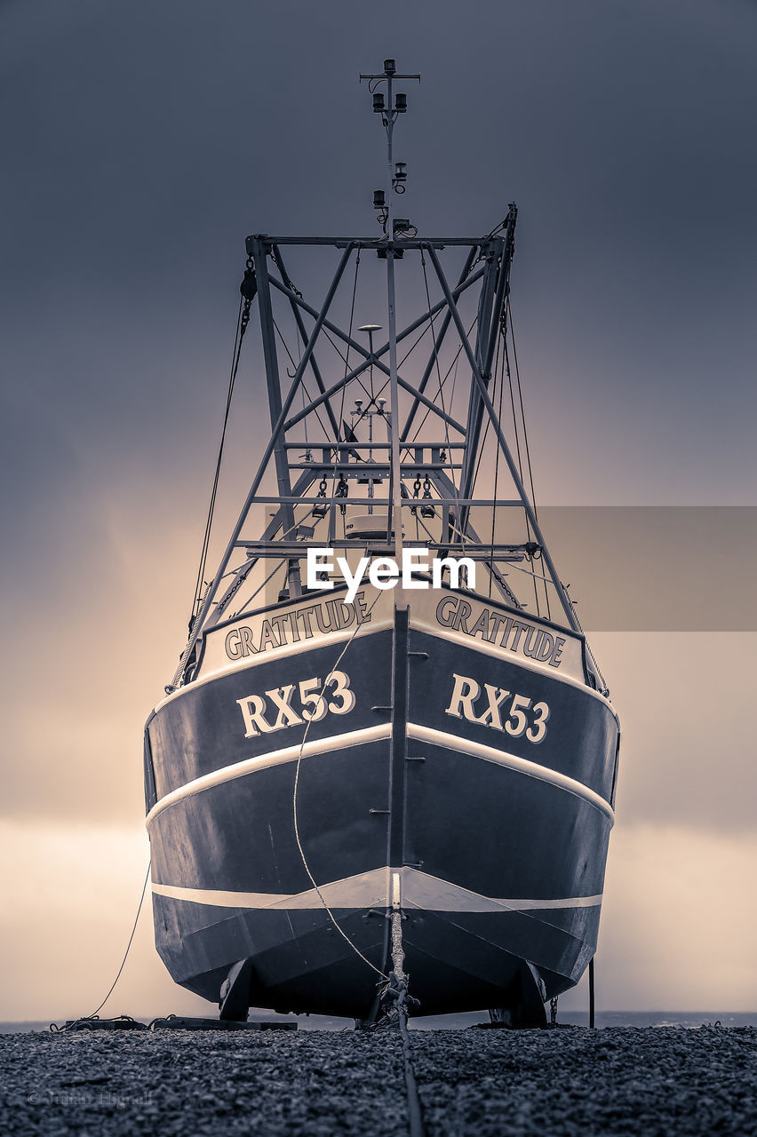 SAILBOAT MOORED ON SEA SHORE AGAINST SKY