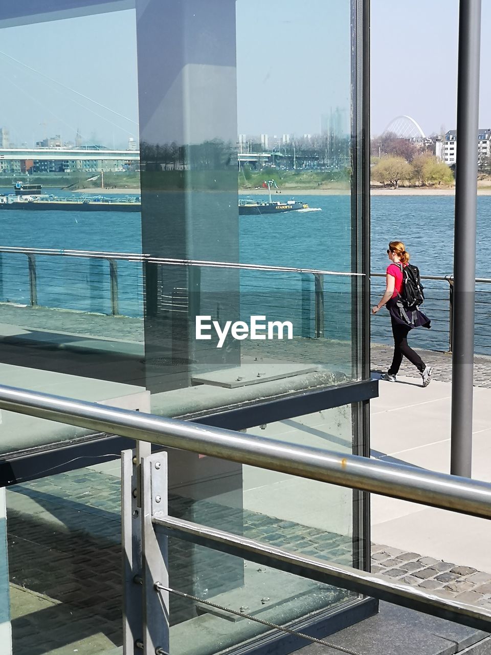 WOMAN STANDING BY RAILING BY WINDOW