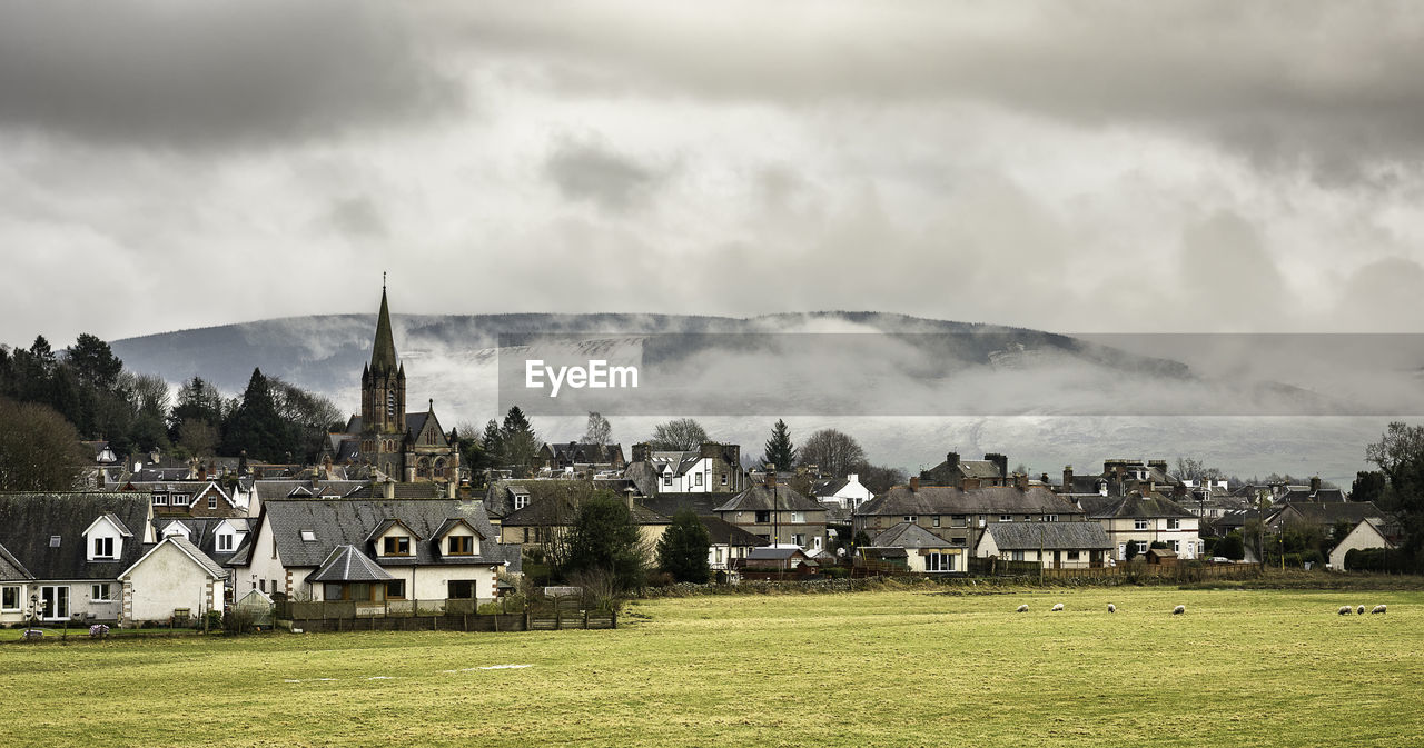 Houses in town against cloudy sky