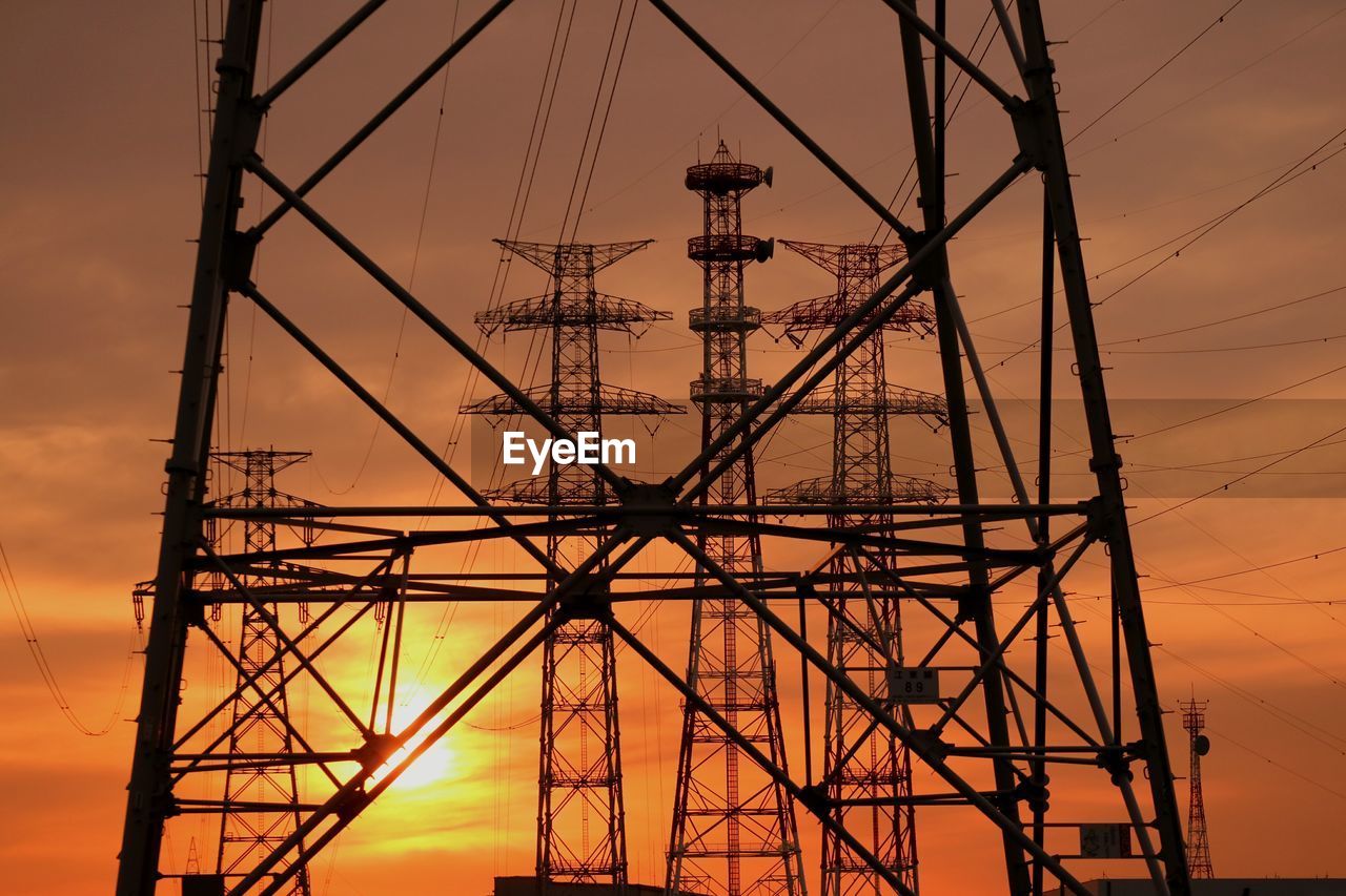 Low angle view of electricity pylon at sunset