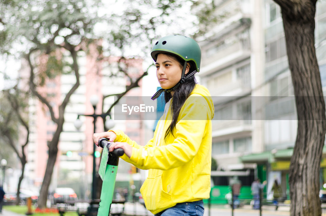 Young woman with push scooter in city