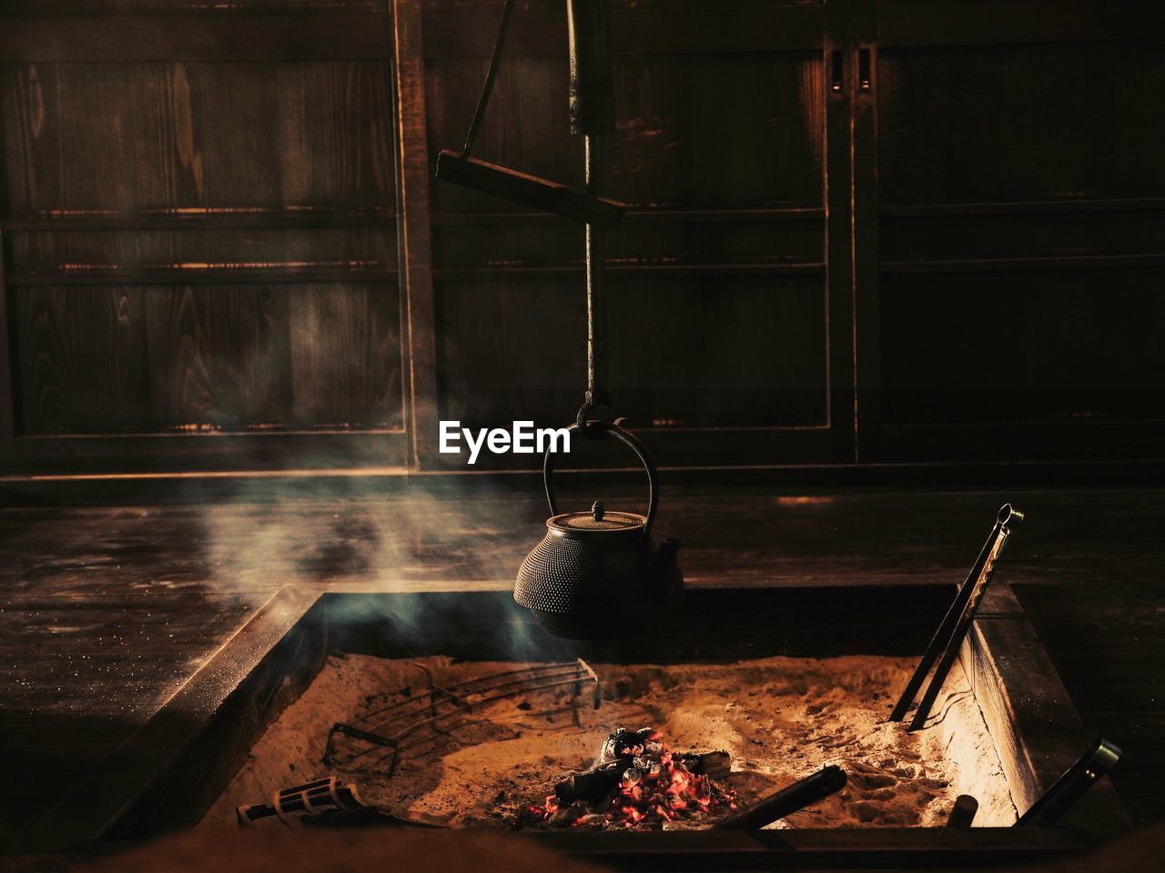 Kettle hanging over fire pit in room