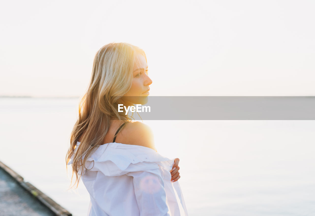 Young woman looking at sea against sky