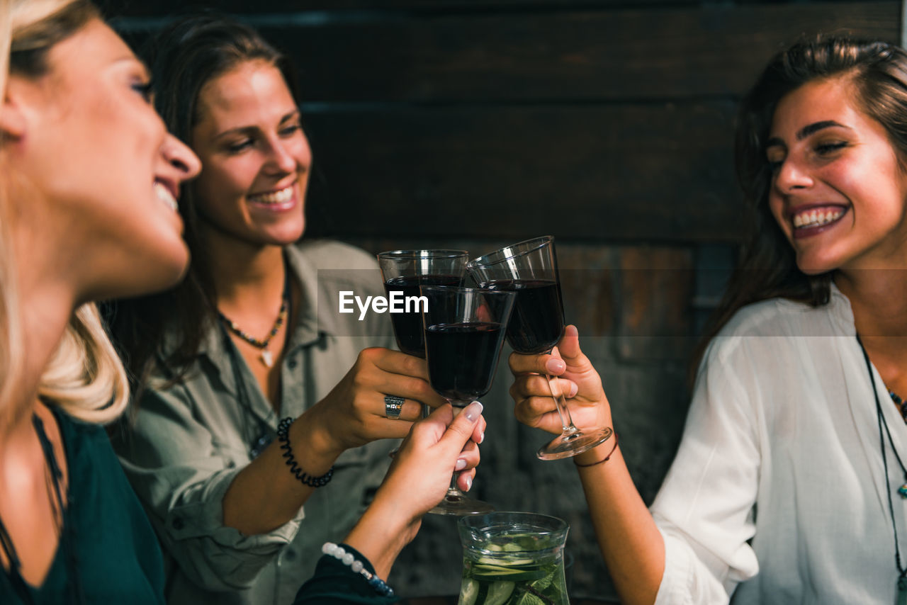Female friends toasting wineglasses at outdoors restaurant during night