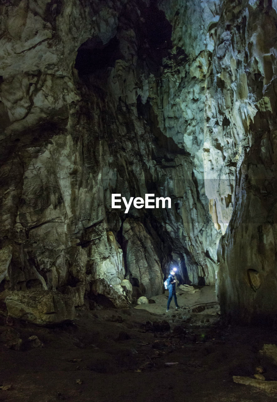 Man with illuminated head lamp exploring cave