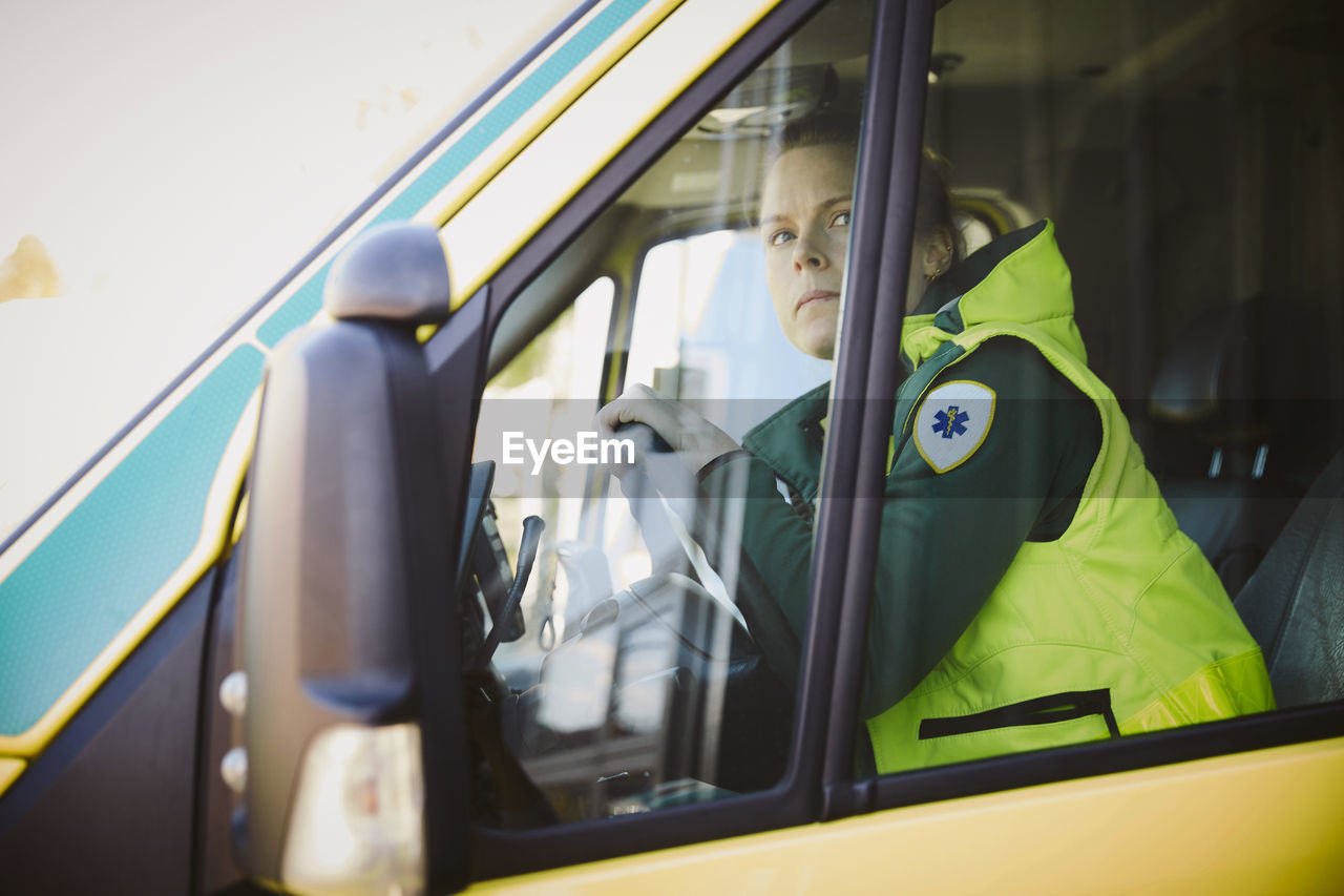 Female thoughtful rescue worker looking away while sitting in ambulance