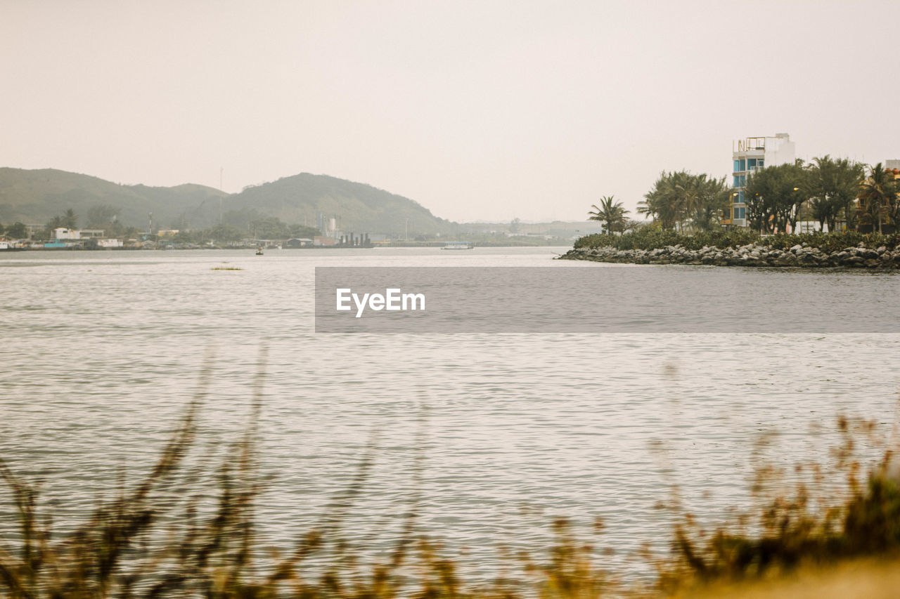 SCENIC VIEW OF SEA BY MOUNTAINS AGAINST CLEAR SKY