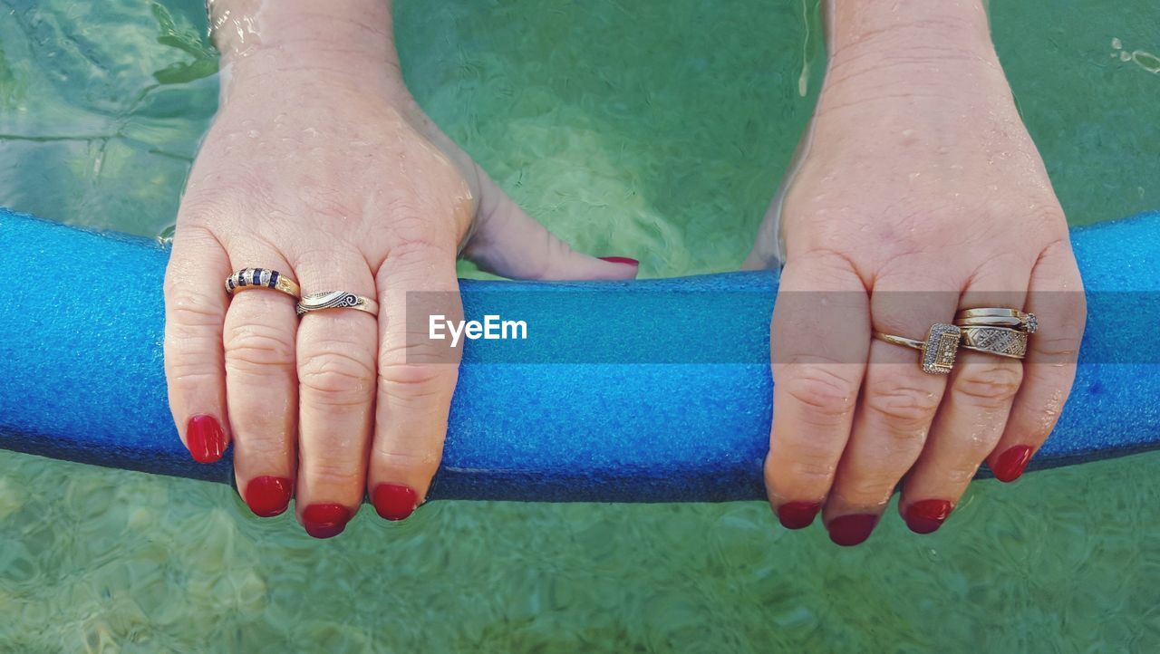 Cropped hands holding inflatable object in swimming pool