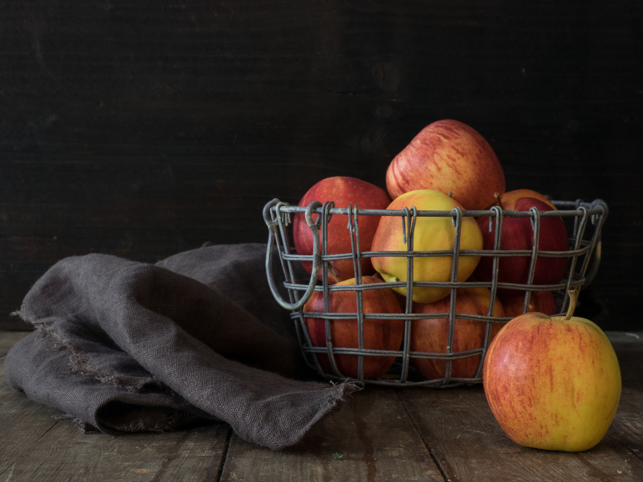 Close-up of apples in basket on table against black background