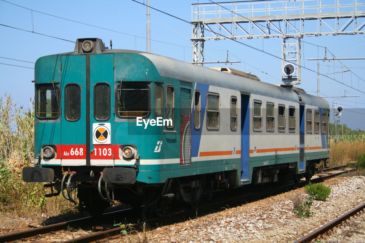 TRAIN ON RAILROAD TRACK AGAINST CLEAR SKY