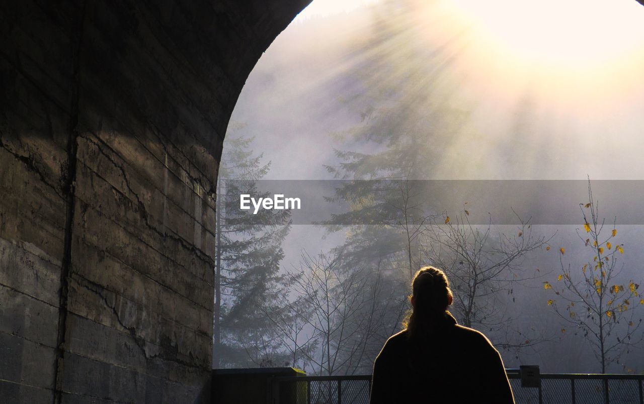 Rear view of woman standing in tunnel